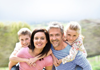 Parents giving piggyback ride to kids outside