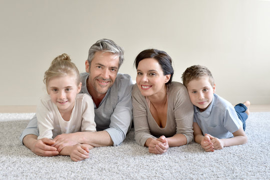 Portrait of cheerful family laying on carpet