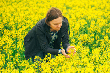 Fototapeta premium Agronomist woman examining oilseed rape flower blooming