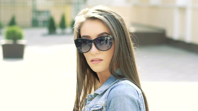 Sexy girl in sunglasses looking on camera on sunshine background. Slowly