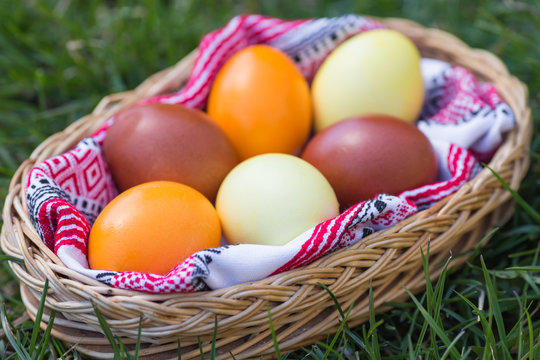 Unique hand painted Easter eggs in basket on grass. Traditional decoration in sun light