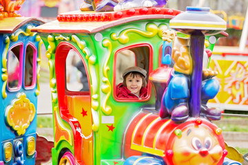 Beautiful boy having fun on the ride at the amusement park