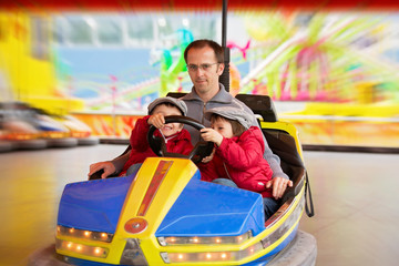 Father and his two sons, having a ride in the bumper car