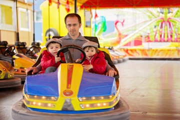 Obraz na płótnie Canvas Father and his two sons, having a ride in the bumper car