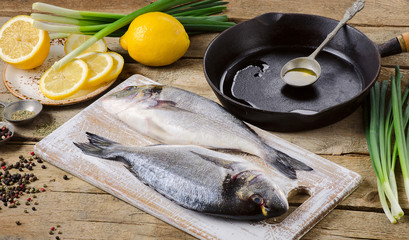 Fresh uncooked dorado or sea bream on rustic wooden board.