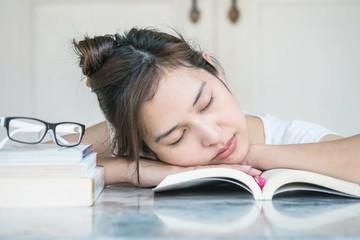 Woman sleeping after she tired for reading with a book on marble table in front of house