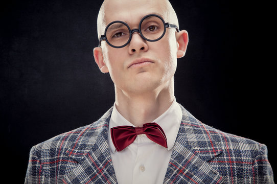 Young alluring bald caucasian man professor or teacher with red bow tie and glasses black isolated