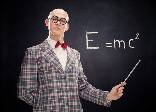 bald caucasian professor or teacher with bow tie and glasses point stick on blackboard with Einstein formula