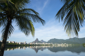 Scenic skyline morning view of Lagoa Rodrigo de Freitas lagoon in Rio de Janeiro Brazil with Ipanema and Leblon reflecting between palm trees on the calm horizon 