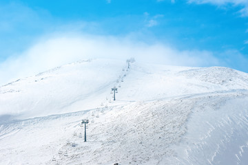 Obraz premium beautiful winter landscape of Dombaj mountains with blue sky, clouds and cableway, Russia