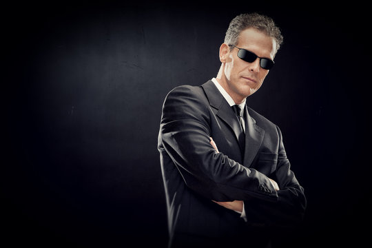 businessman with black suit and sunglasses isolated on black