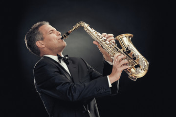 Fototapeta na wymiar handsome businessman play saxophone isolated on black