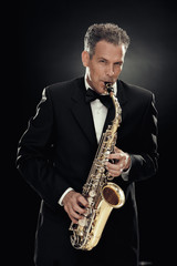Fototapeta na wymiar handsome businessman play saxophone isolated on black