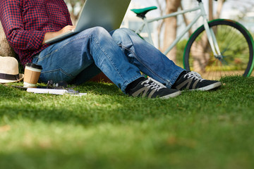Cropped image of man sitting in park and working on laptop
