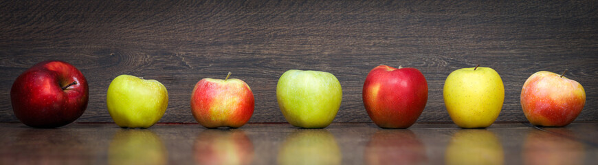 Lots of variety of apples - green and red on a wooden floor. Panorama