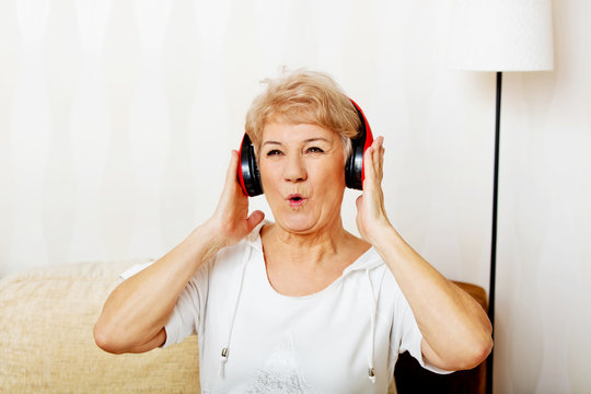 Happy senior woman wearing red headphones 