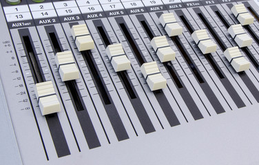 close-up of a metallic music mixer with control knobs forming a wave pattern