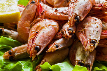 Big boiled shrimps and lemon on green lettuce.