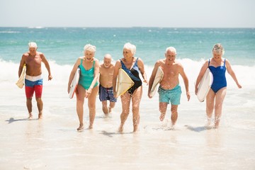 Seniors holding surfboards at the beach