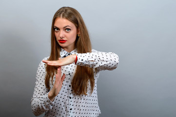 Young woman showing time out hand gesture, isolated on grey wall background.