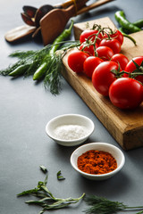 Tomatoes with green pappers and herbs on gray