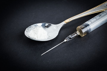 Drug syringe and cooked heroin on spoon