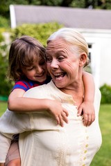 Grandmother carrying grandson at yard 