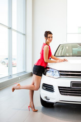 Fototapeta na wymiar Beautiful girl in a short skirt is standing next to a white car