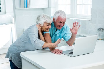 Happy senior couple gesturing while using laptop 