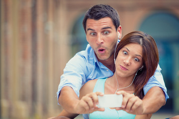 young brunette couple having fun together with smartphone at park