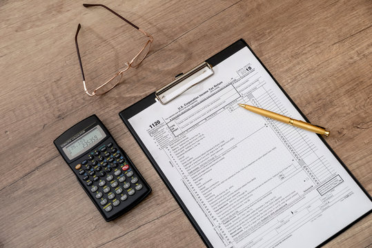 US 1120 tax form, pen, calclator on desk