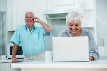 Happy senior man holding paper while talking on phone