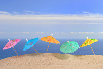 Fototapeta na wymiar Cocktail umbrellas on a beach sand