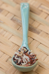 Mix rices : white (jasmine) rice,riceberry and brown rice on blue spoon, on threshing basket