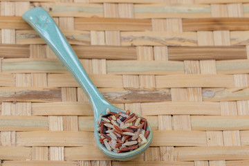 Mix rices : white (jasmine) rice,riceberry and brown rice on blue spoon, on threshing basket