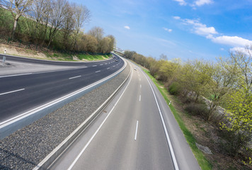 leere Autobahn, leicht schräg fotografiert, mit blauem Himmel