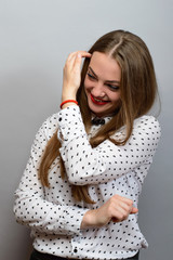 The woman straightens her hair. On a gray background.