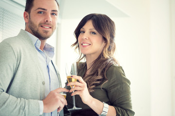young casual couple cheers with champagne in the kitchen