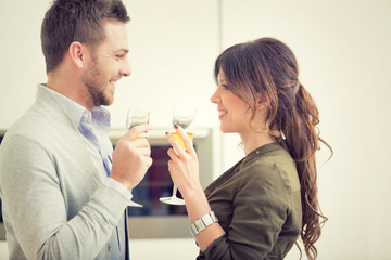 young casual couple cheers with champagne and phone in the kitchen