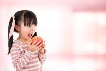 asian smiling little girl eat a apple isolated on pink background