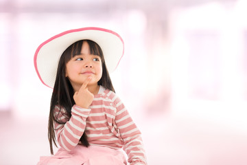 asian smiling little girl with hat on pink background