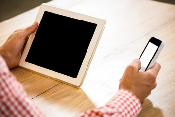 Man text messaging on mobile phone and holding digital tablet