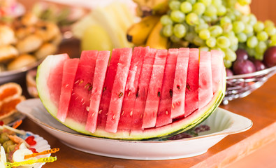 Sliced watermelon on a dish. Healthy food for vegetarians. Festive table setting with fruit and berries.