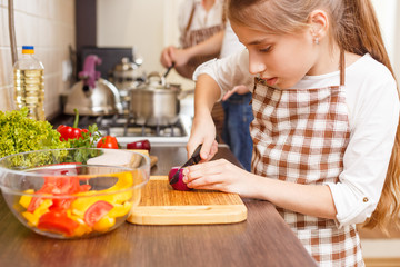 Small girl cutting onion on the kitchen counter