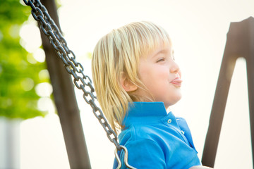 happy smiling blond child play with seesaw in a park