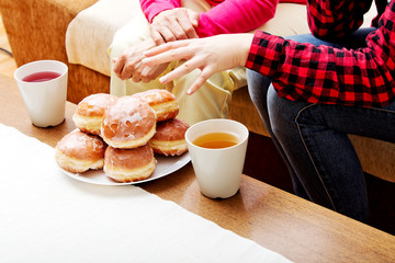 Mother and daughter sitting on couch with donuts and tea on table
