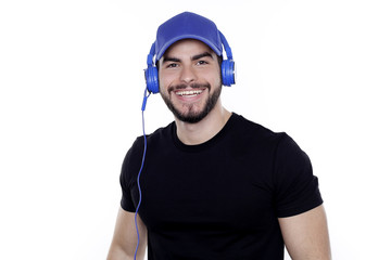 Junger Mann mit Bart trägt schwarzes T-Shirt, Dunkelblaue Kopfhörer und Basecap