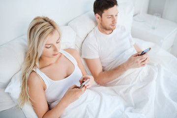 Obraz premium couple with smartphones in bed