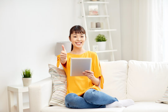 happy asian woman with tablet pc and thumbs up