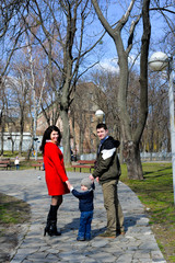 Portrait of happy young family spending time together in green nature in park. Mother, father and son having fun outdoors on a spring sunny day. Concept of happy family life, love and happiness. 